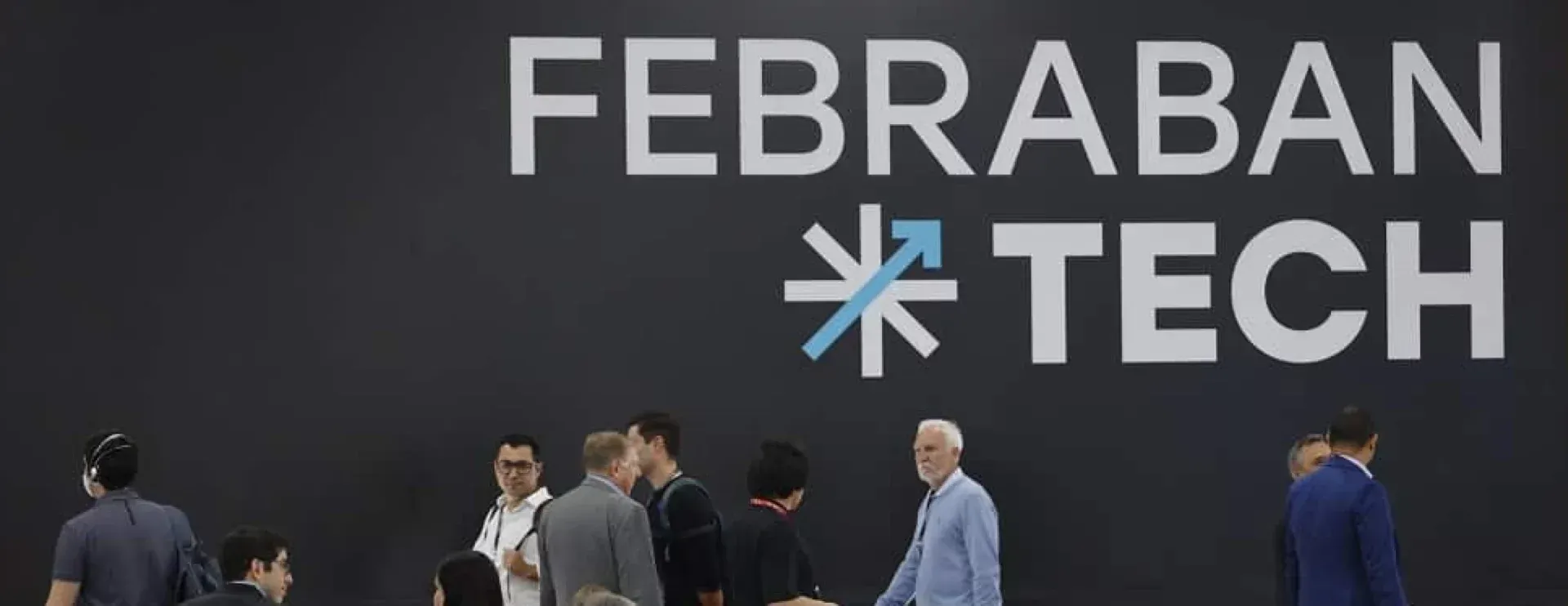 A group of people standing in front of a febraban tech sign