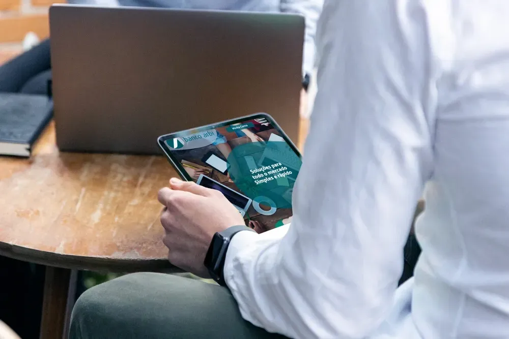 A man is sitting at a table using a tablet computer.