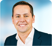 A man in a suit and white shirt is smiling for the camera.