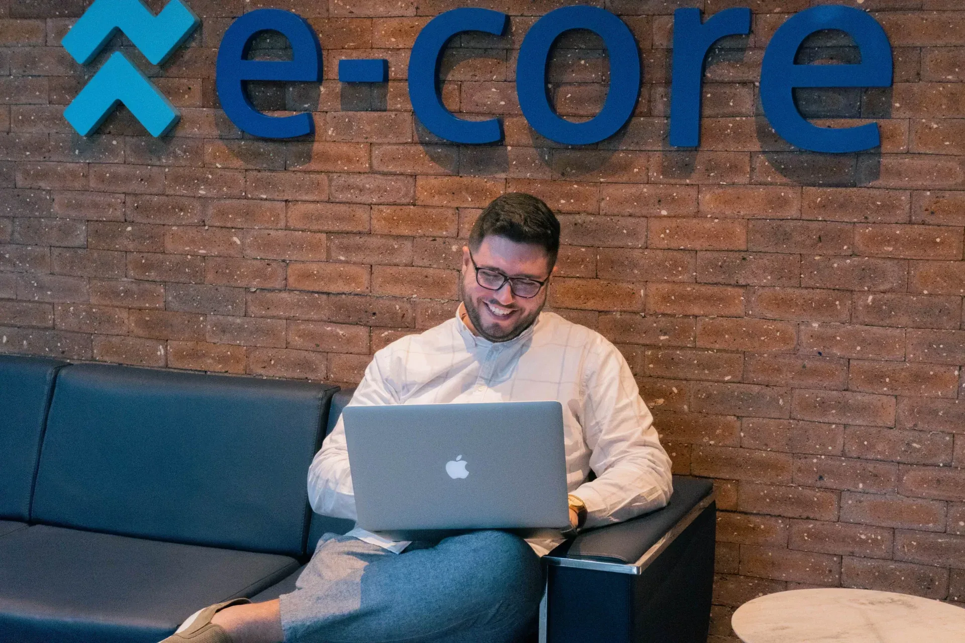 A man is sitting on a couch using a laptop computer.