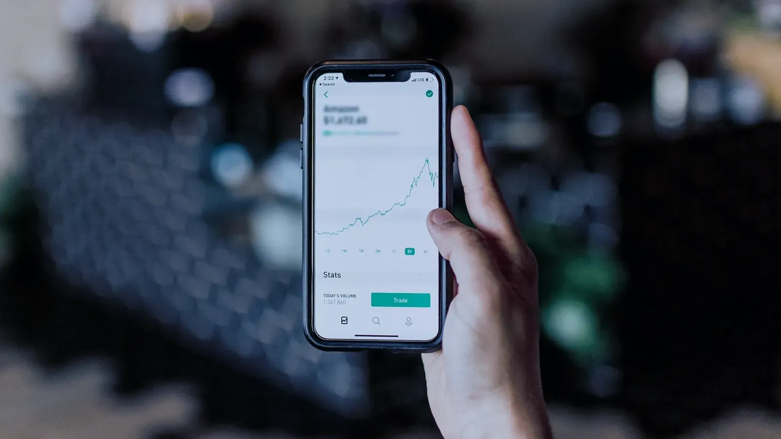 A person is holding a cell phone with a graph on the screen.