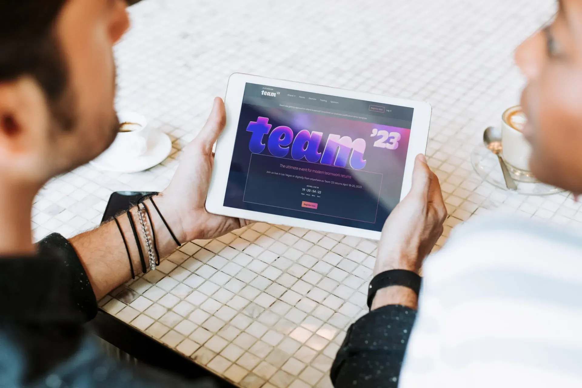 Two people are sitting at a table looking at a tablet.