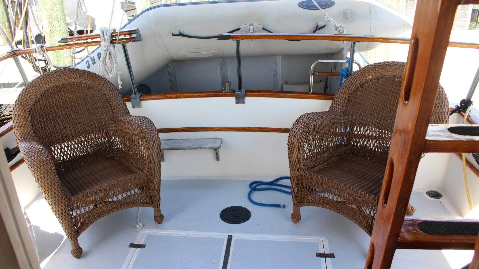 Two wicker chairs on a boat with a boat in the background