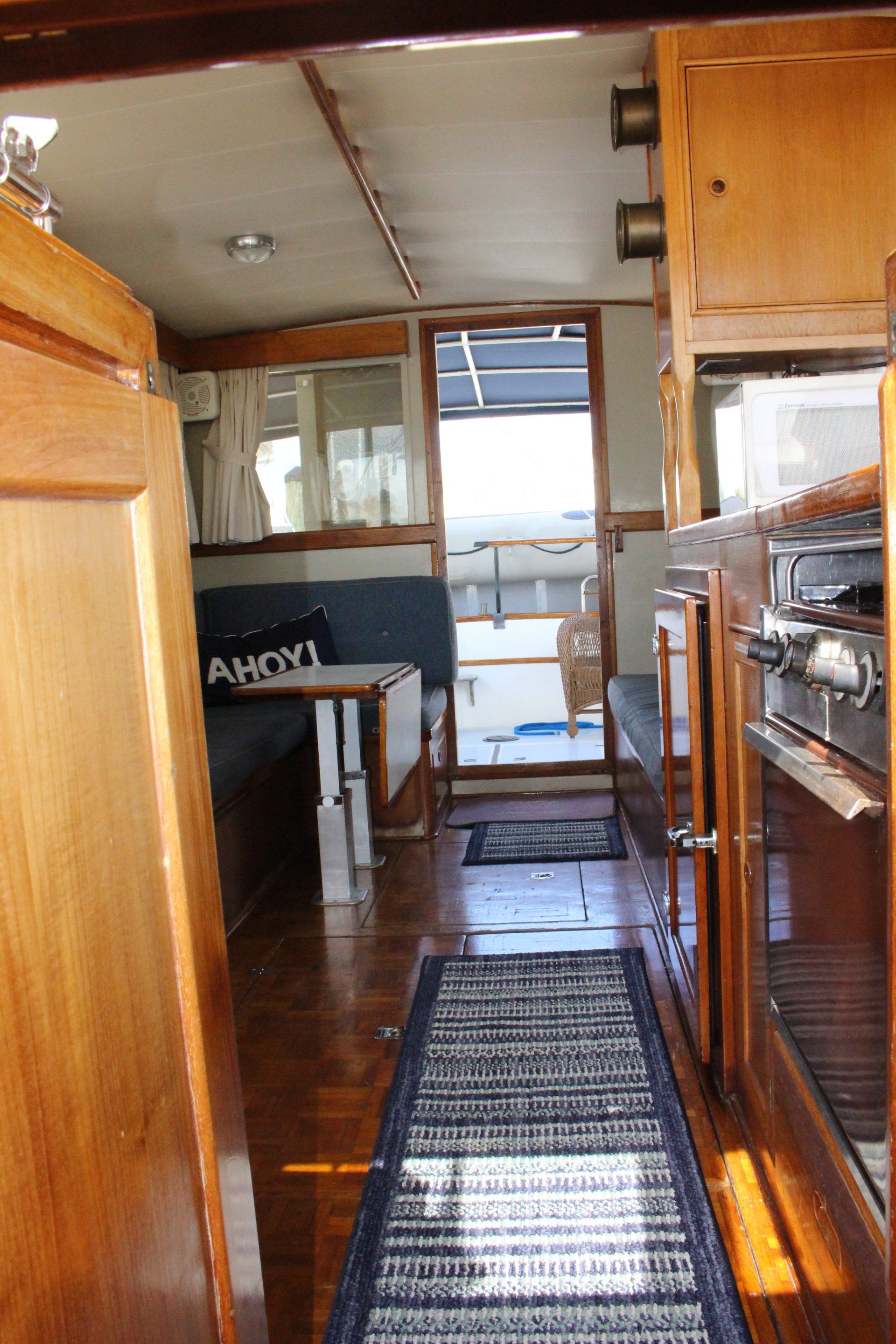 A kitchen on a boat with a table and a rug.