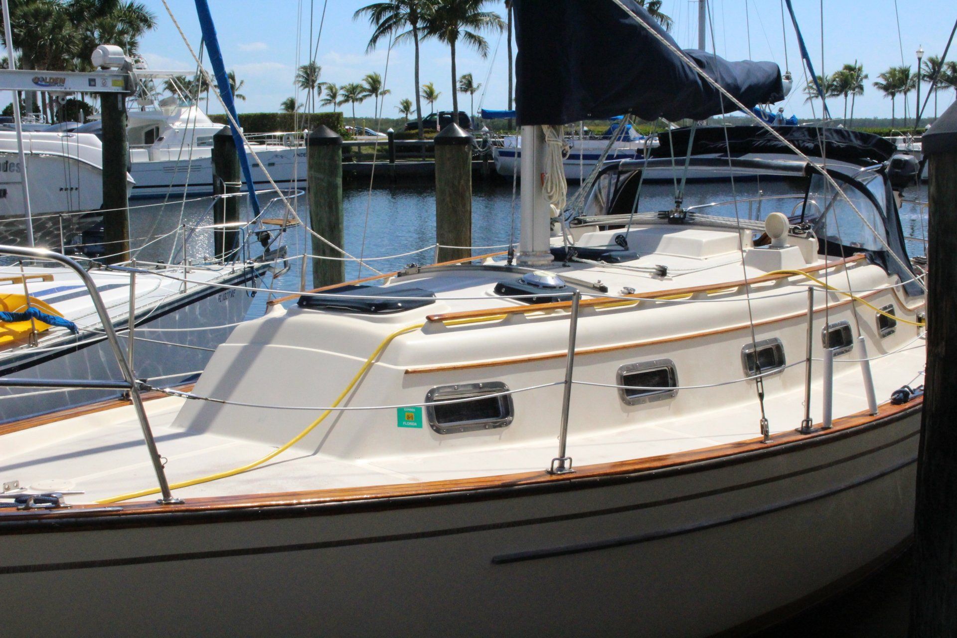 A sailboat with a green sticker on the side is docked in a marina