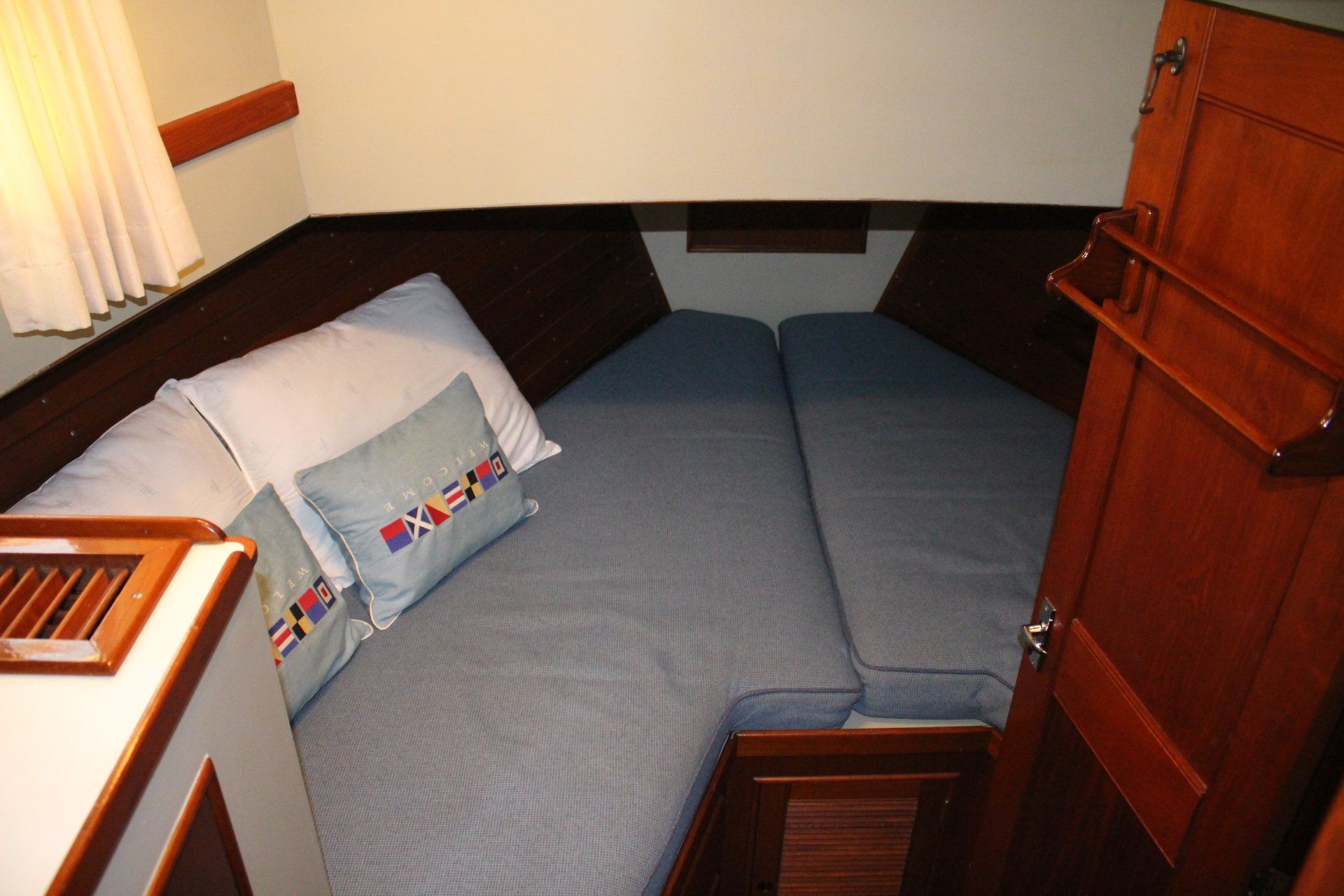 A bed with blue sheets and pillows on a boat
