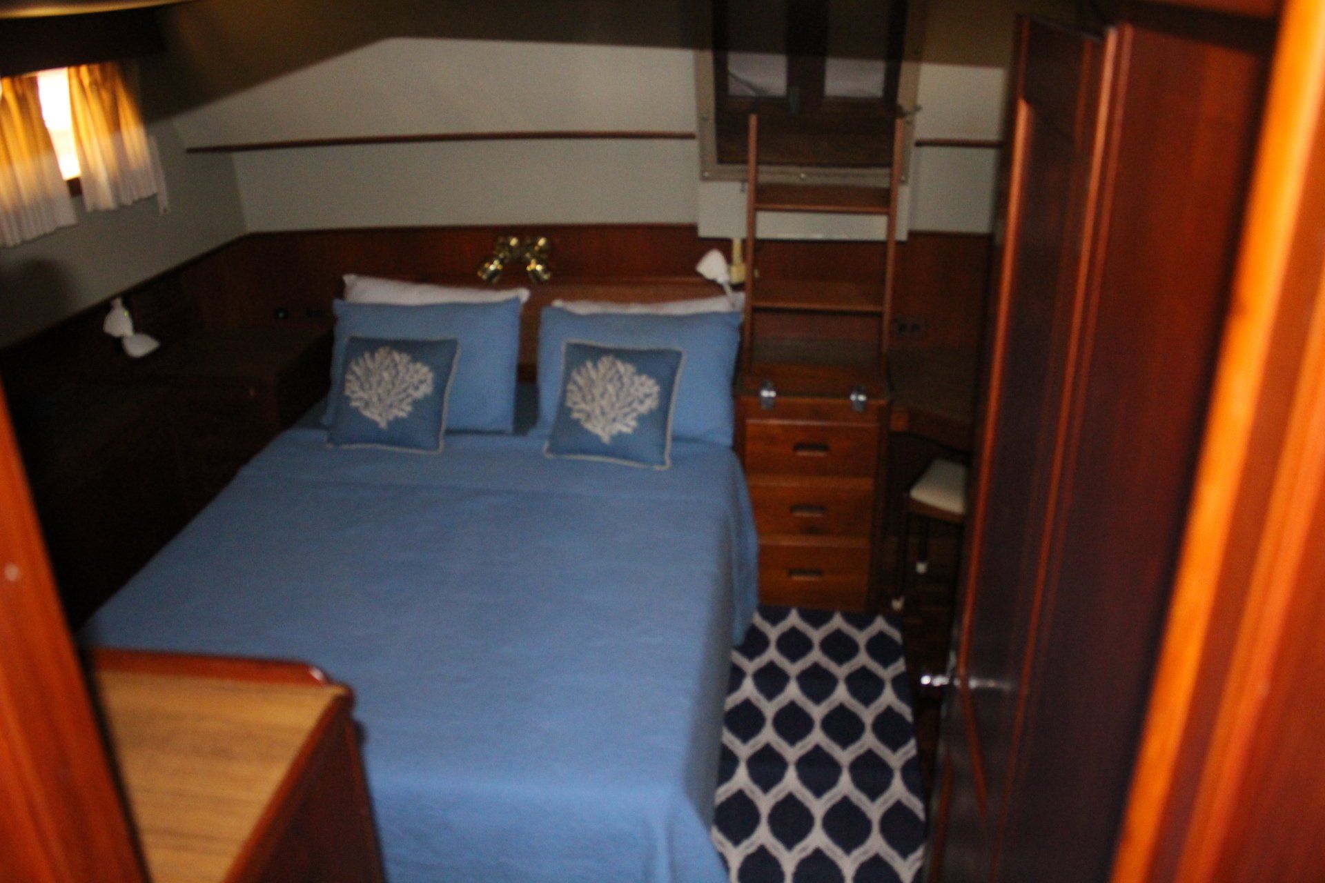 A bedroom on a boat with blue sheets and pillows