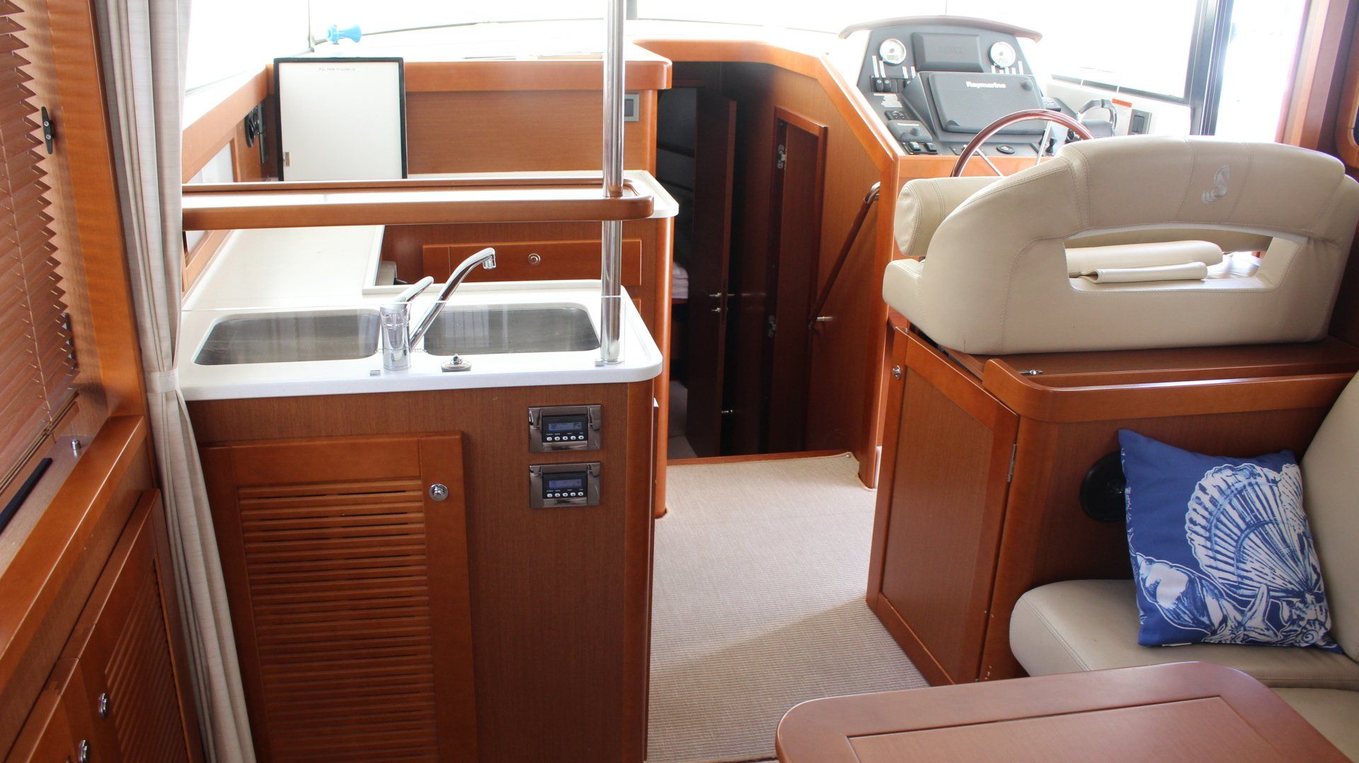 A kitchen with a sink and a steering wheel on a boat