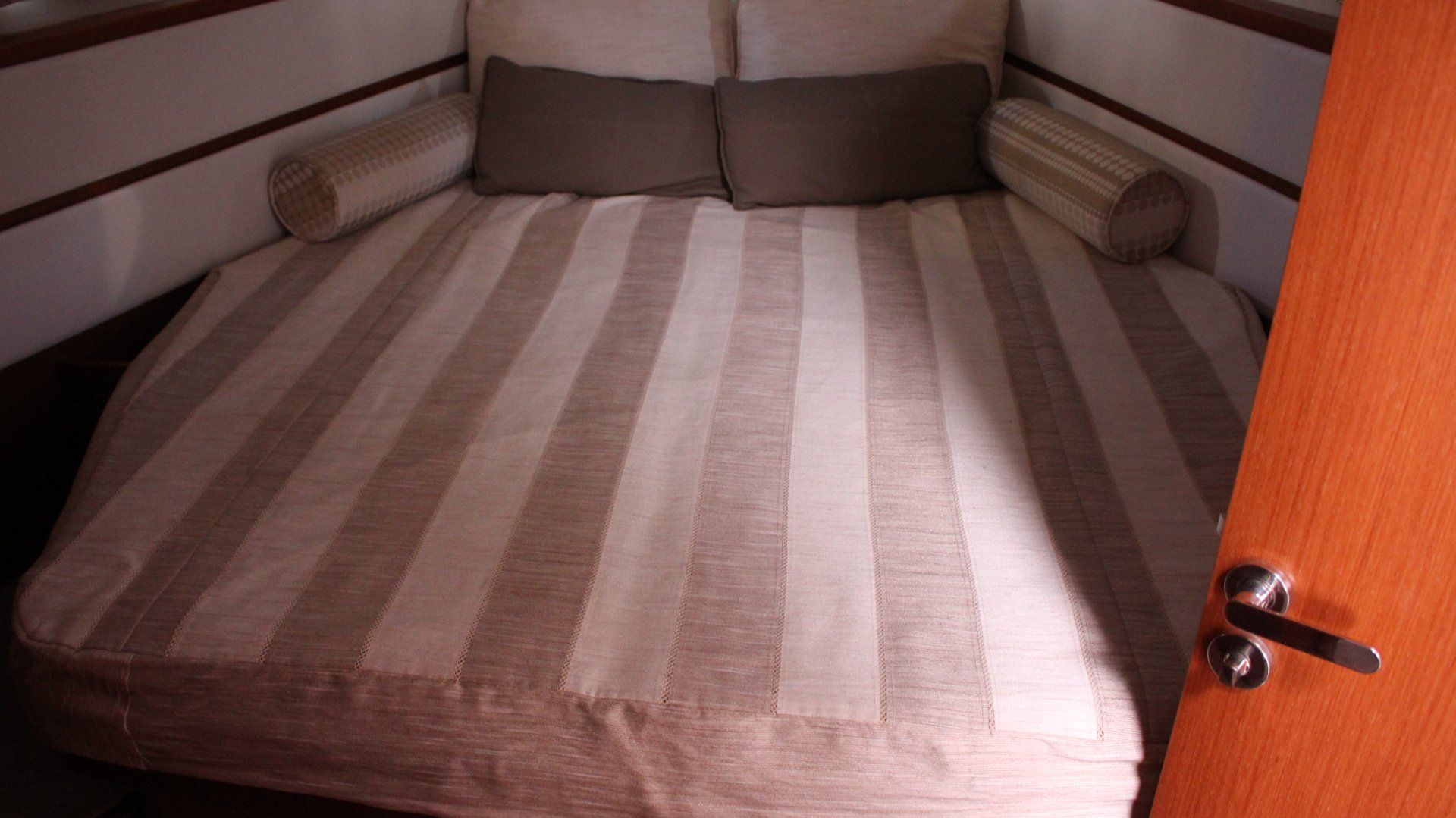 A bed with a striped blanket and pillows in a room next to a door.