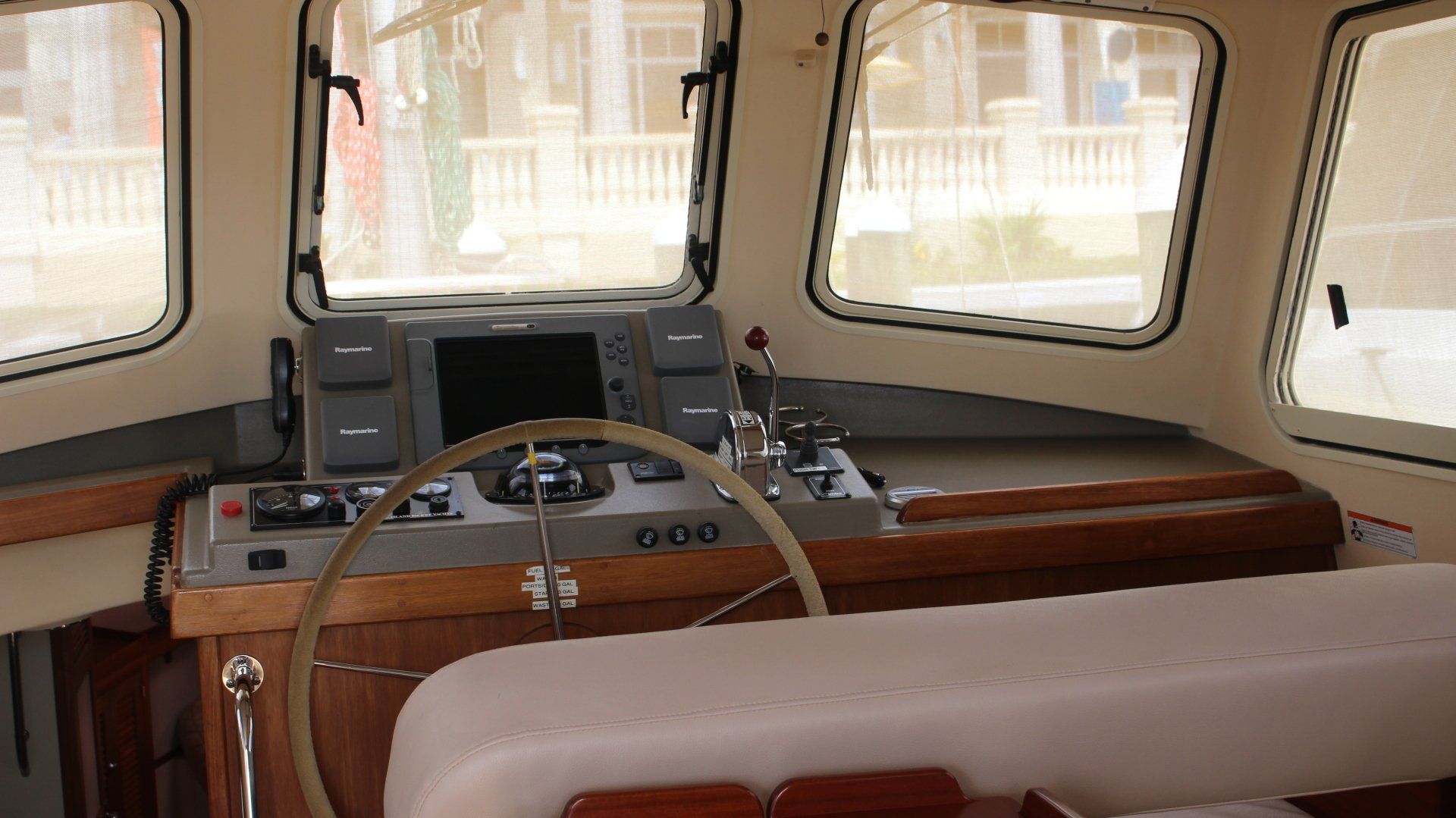 The inside of a boat with a steering wheel and a monitor