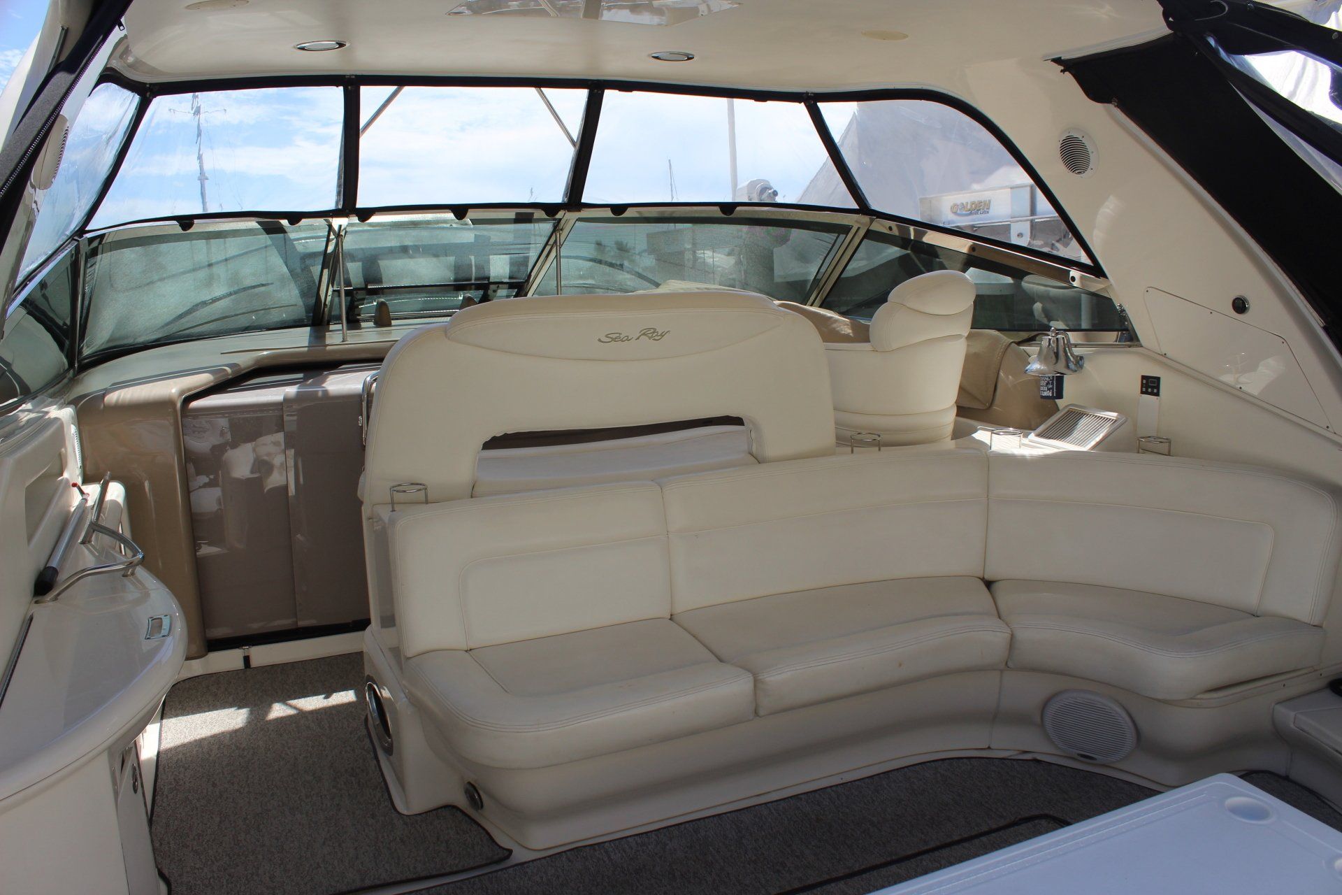 The inside of a boat with a couch and a steering wheel
