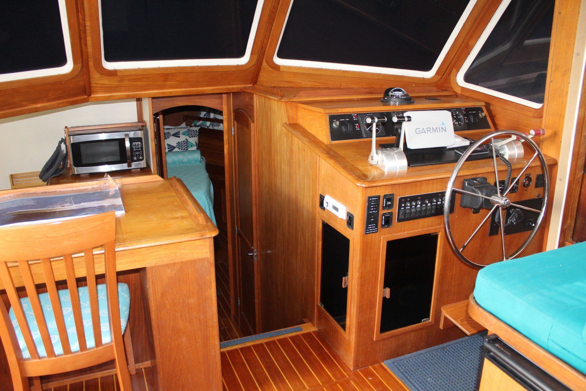The inside of a boat with a steering wheel and a desk