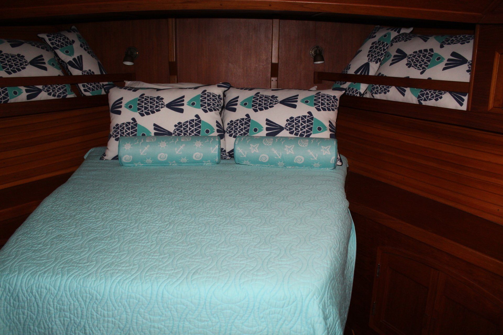 A bed with a blue blanket and fish pillows on it