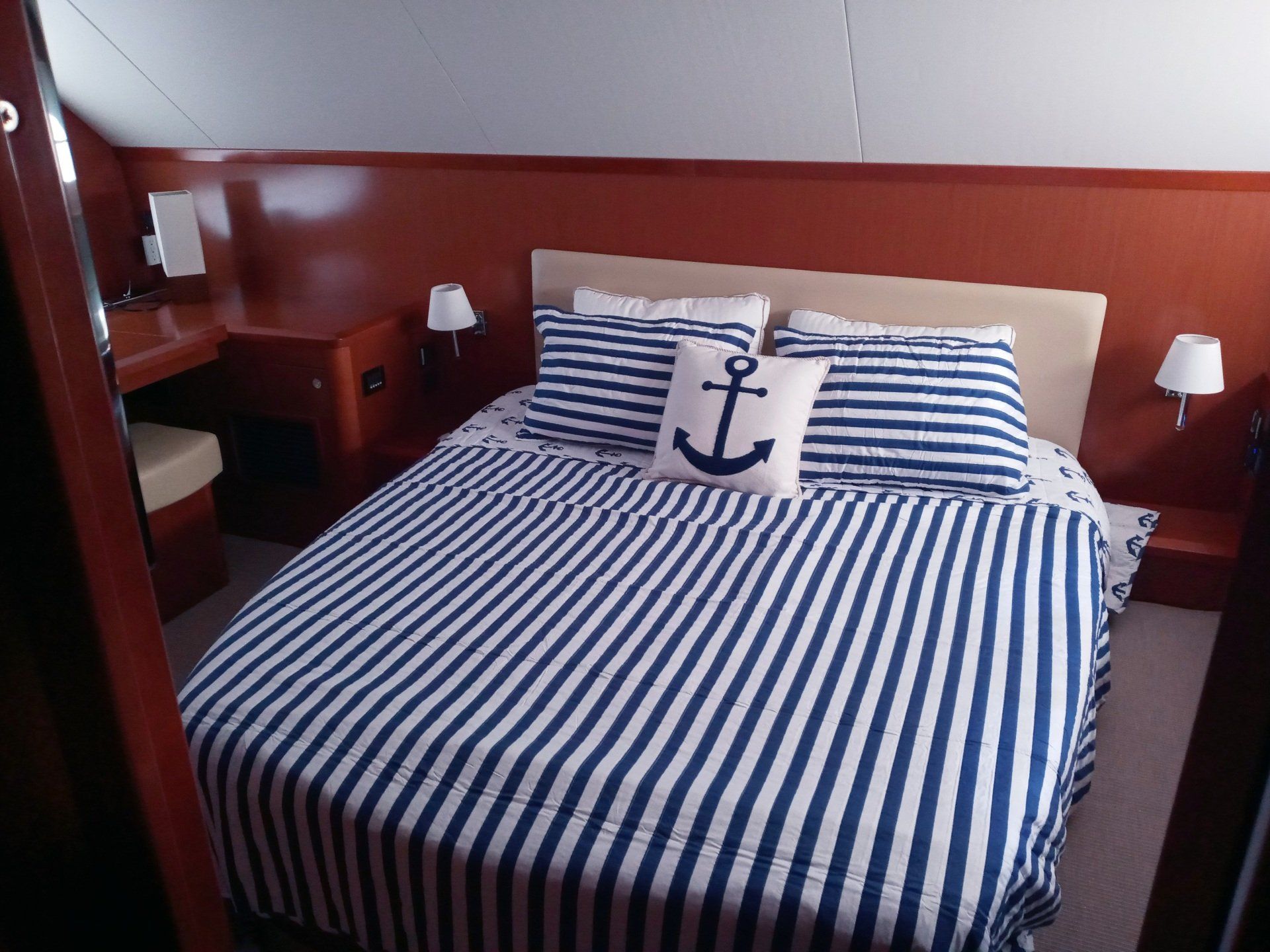 A bed with a striped blanket and pillows with an anchor on it