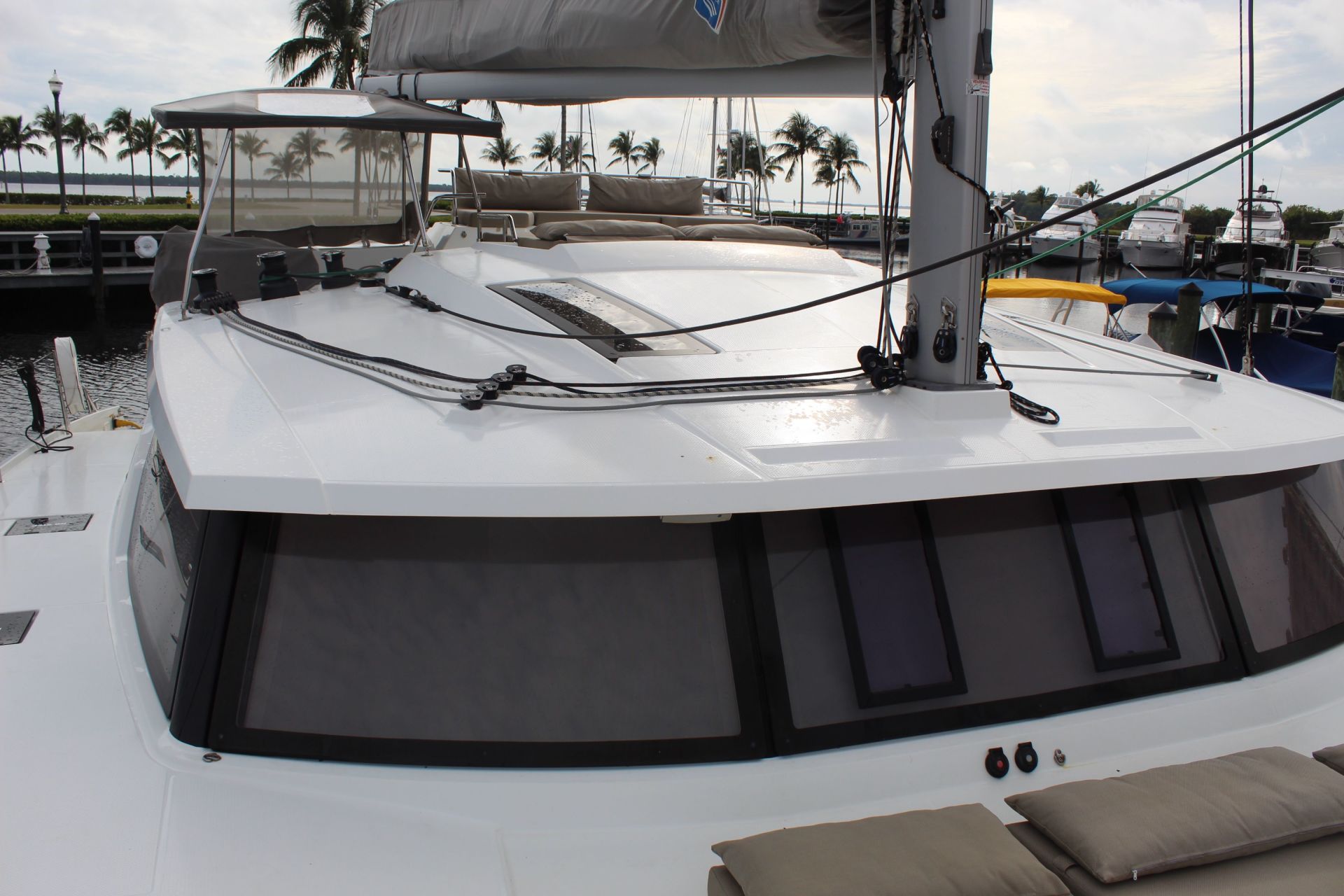A white sailboat is docked in a marina with palm trees in the background.