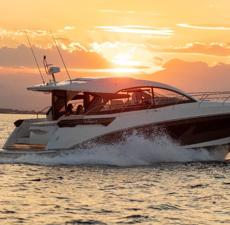 Boat cruising on water at sunset, creating a splash.