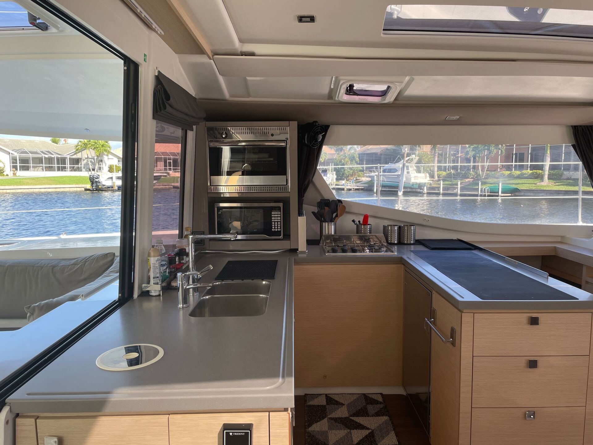 A kitchen on a boat with a sink , stove and oven.