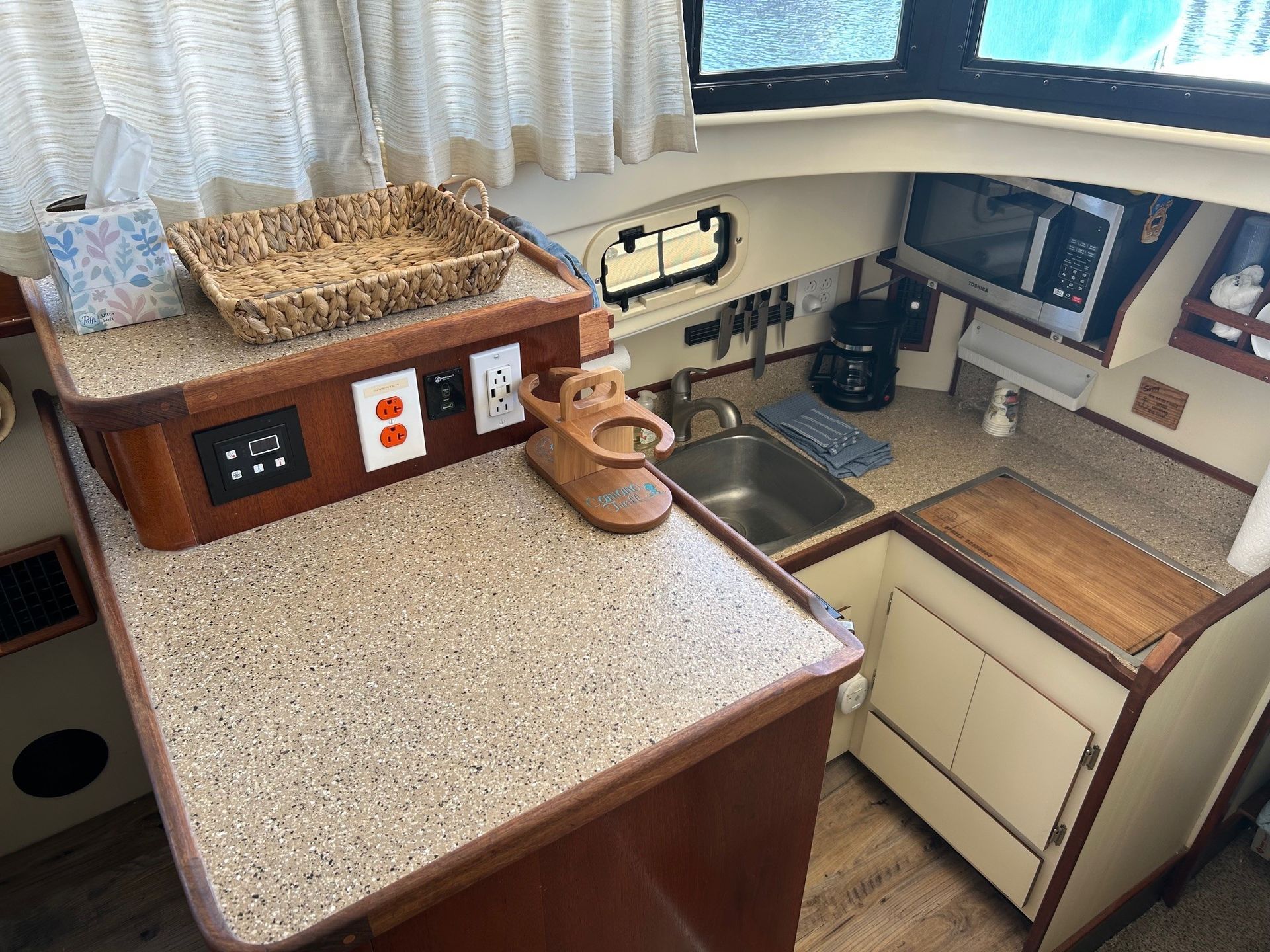 Interior boat galley with a microwave, sink, counter, and wood detailing.