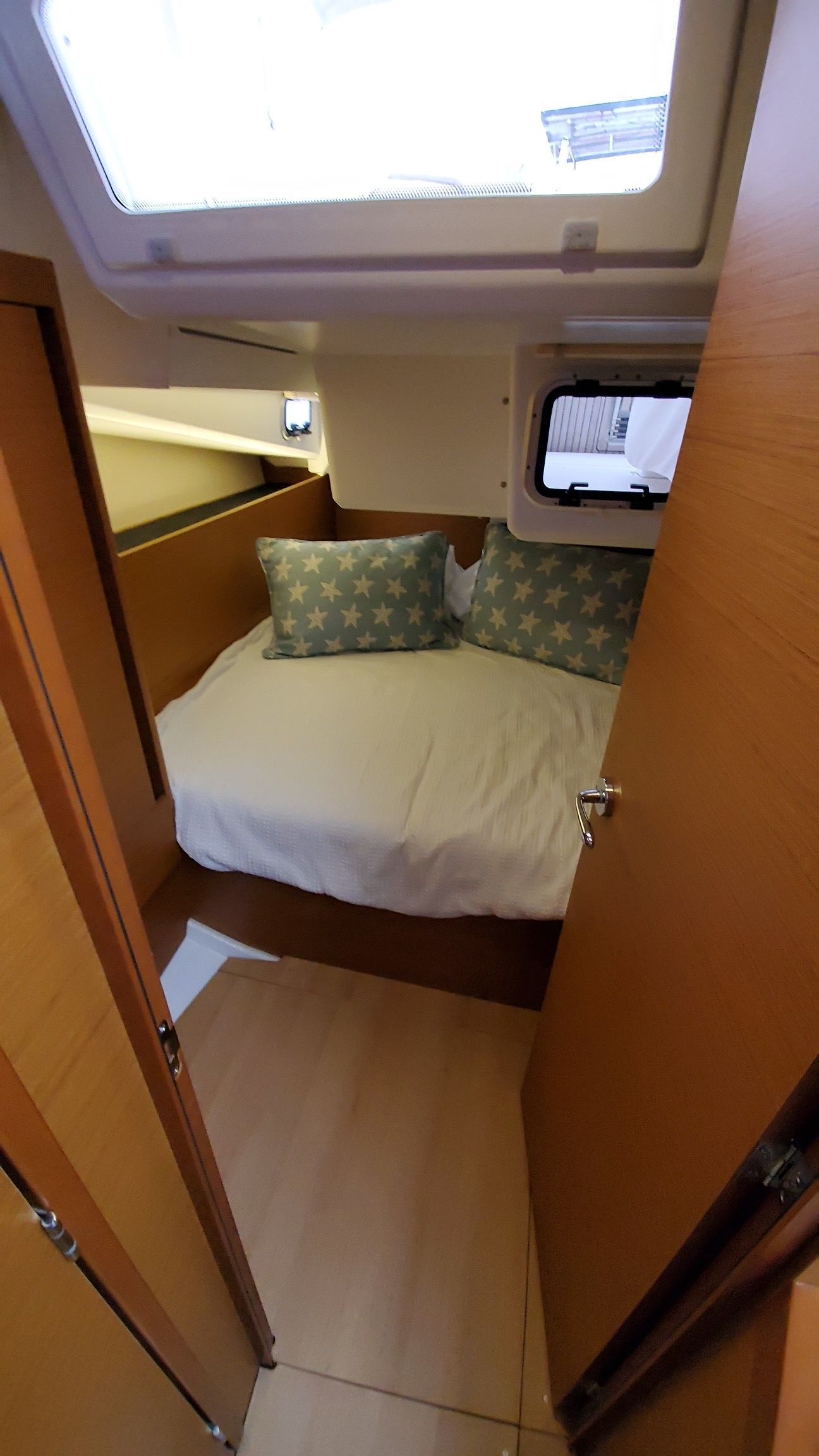 A bedroom on a boat with a bed and a window.