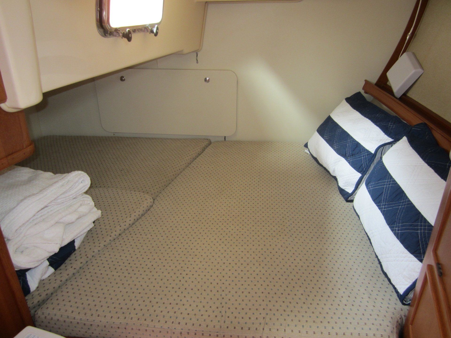A bed on a boat with blue and white striped pillows