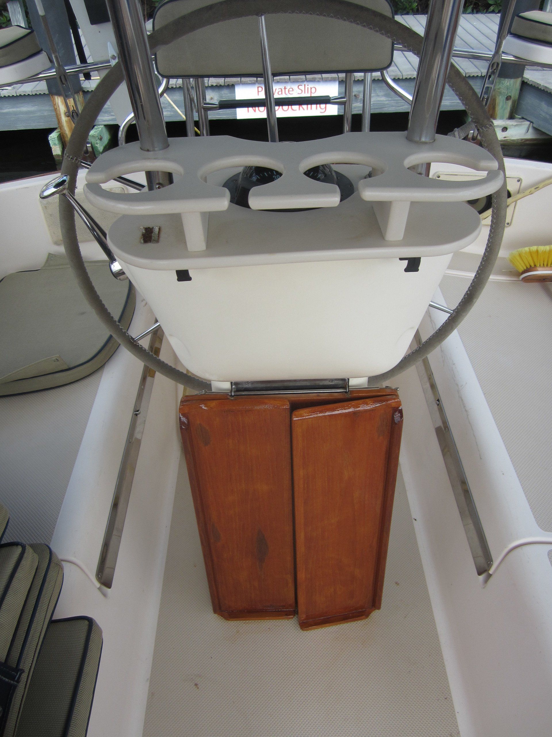 A boat with a steering wheel and a wooden cabinet