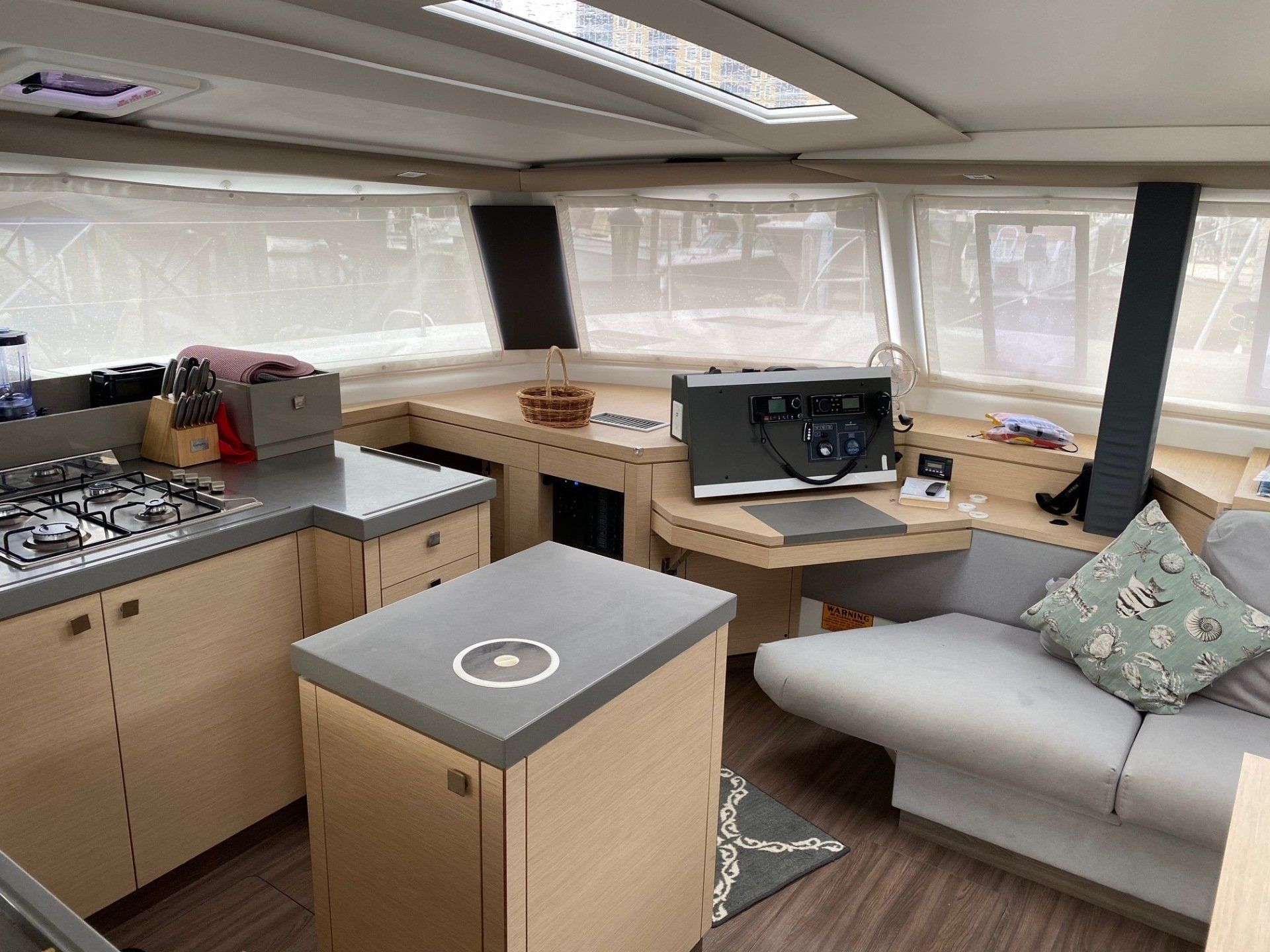 The inside of a boat with a couch , desk , and stove.