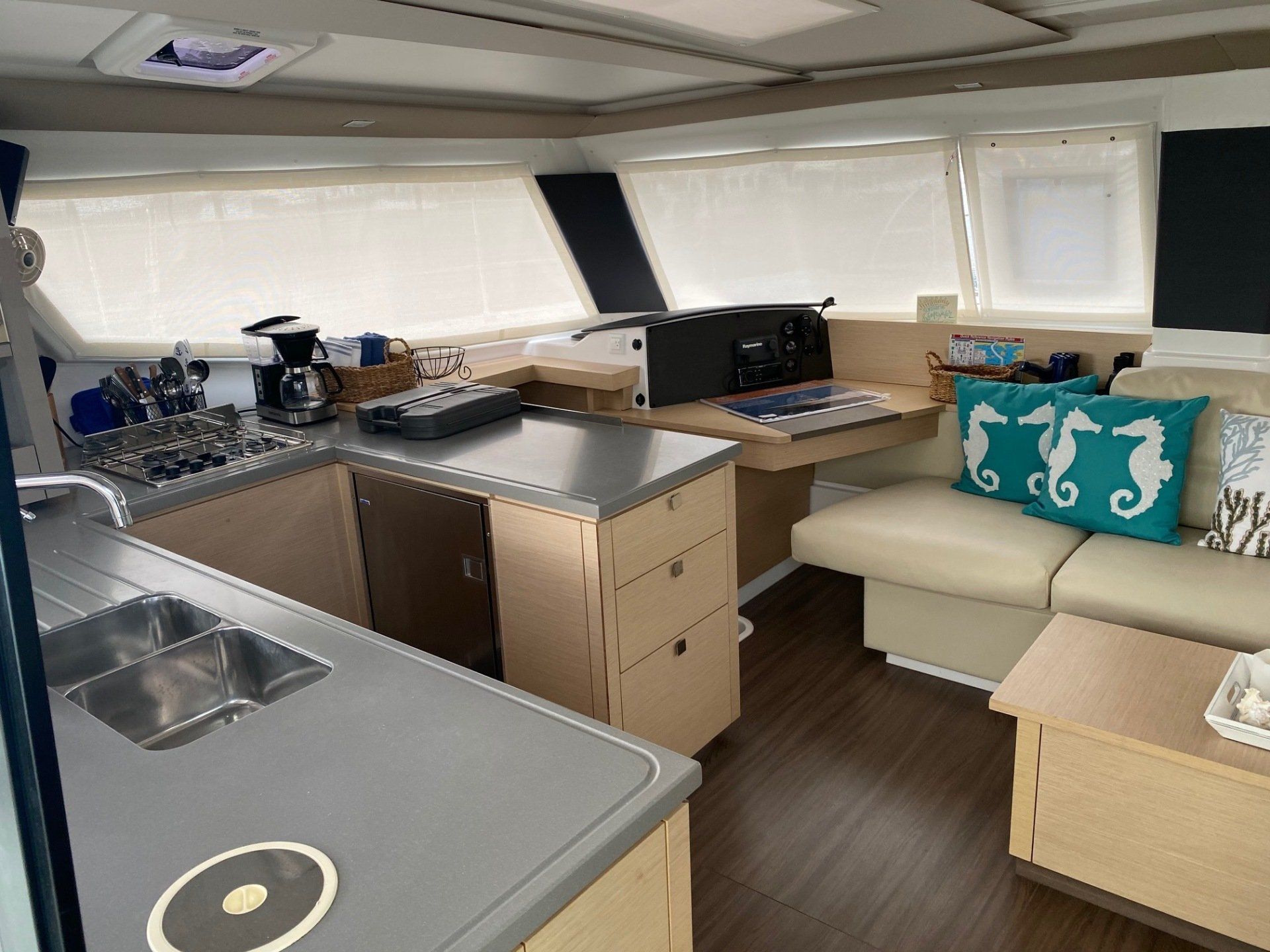 A kitchen and living room on a boat with seahorse pillows on the couch.