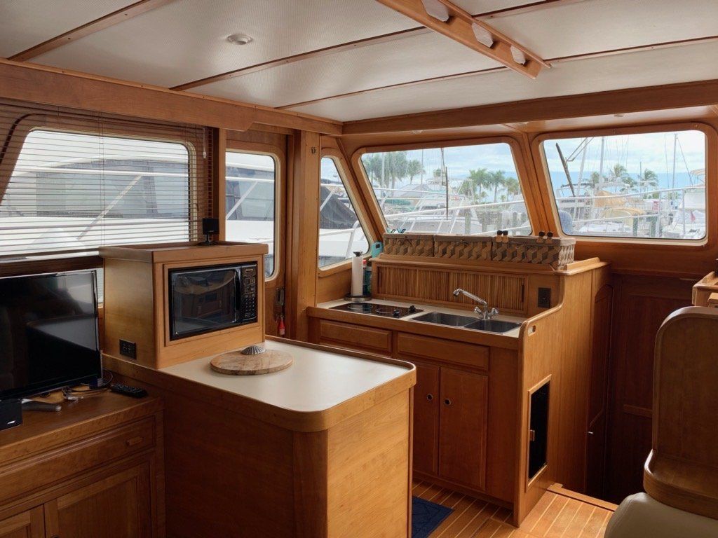 A kitchen on a boat with wooden cabinets and a microwave.