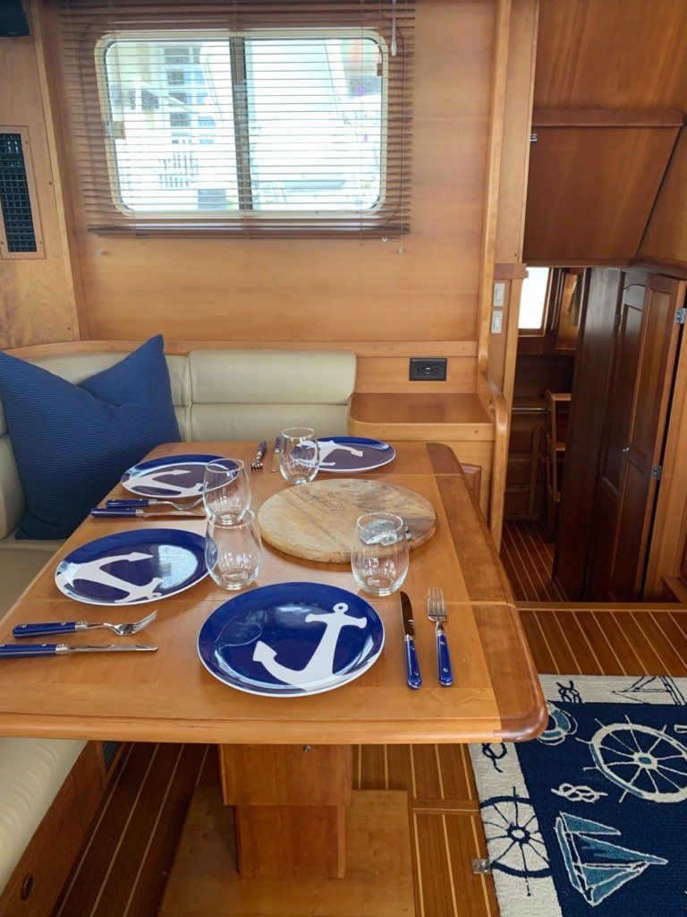 A wooden table with blue plates and silverware on it in a living room on a boat.