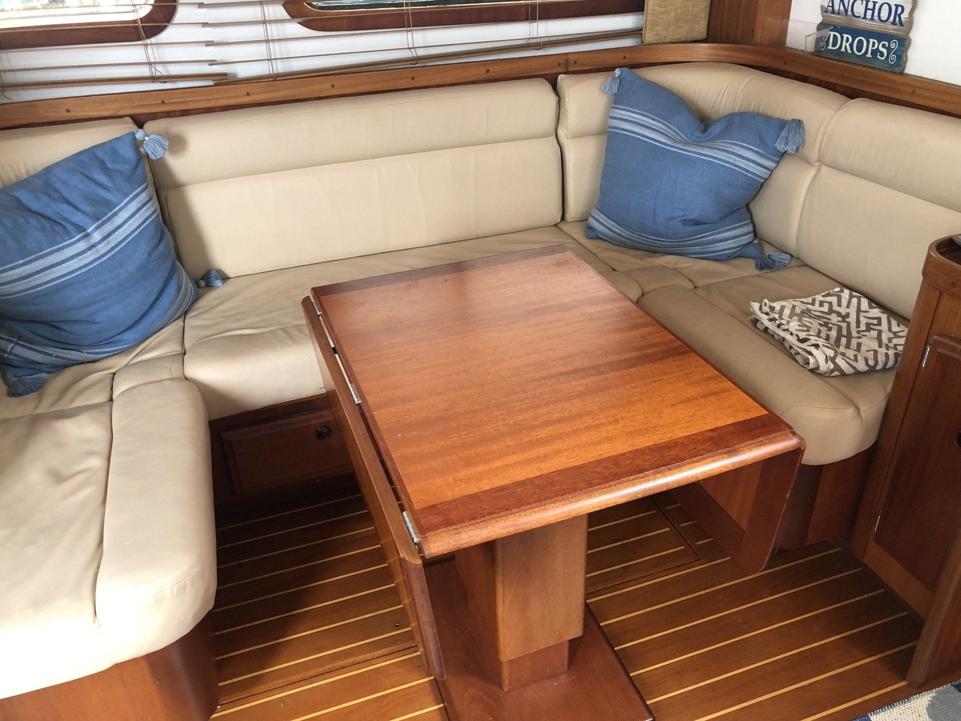 A wooden table is sitting in the middle of a couch on a boat.