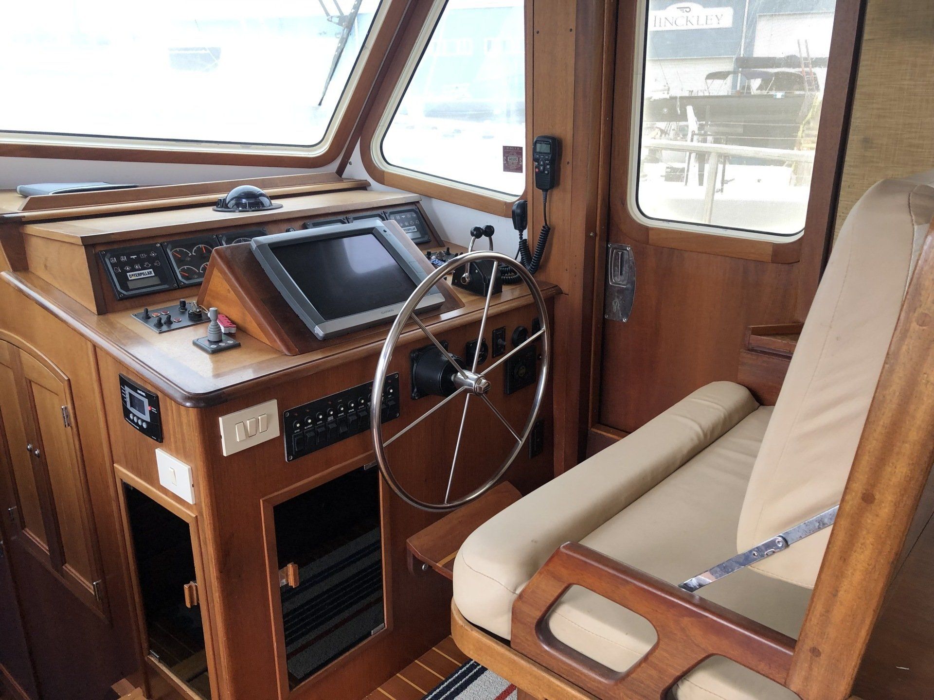 The inside of a boat with a steering wheel and a chair.