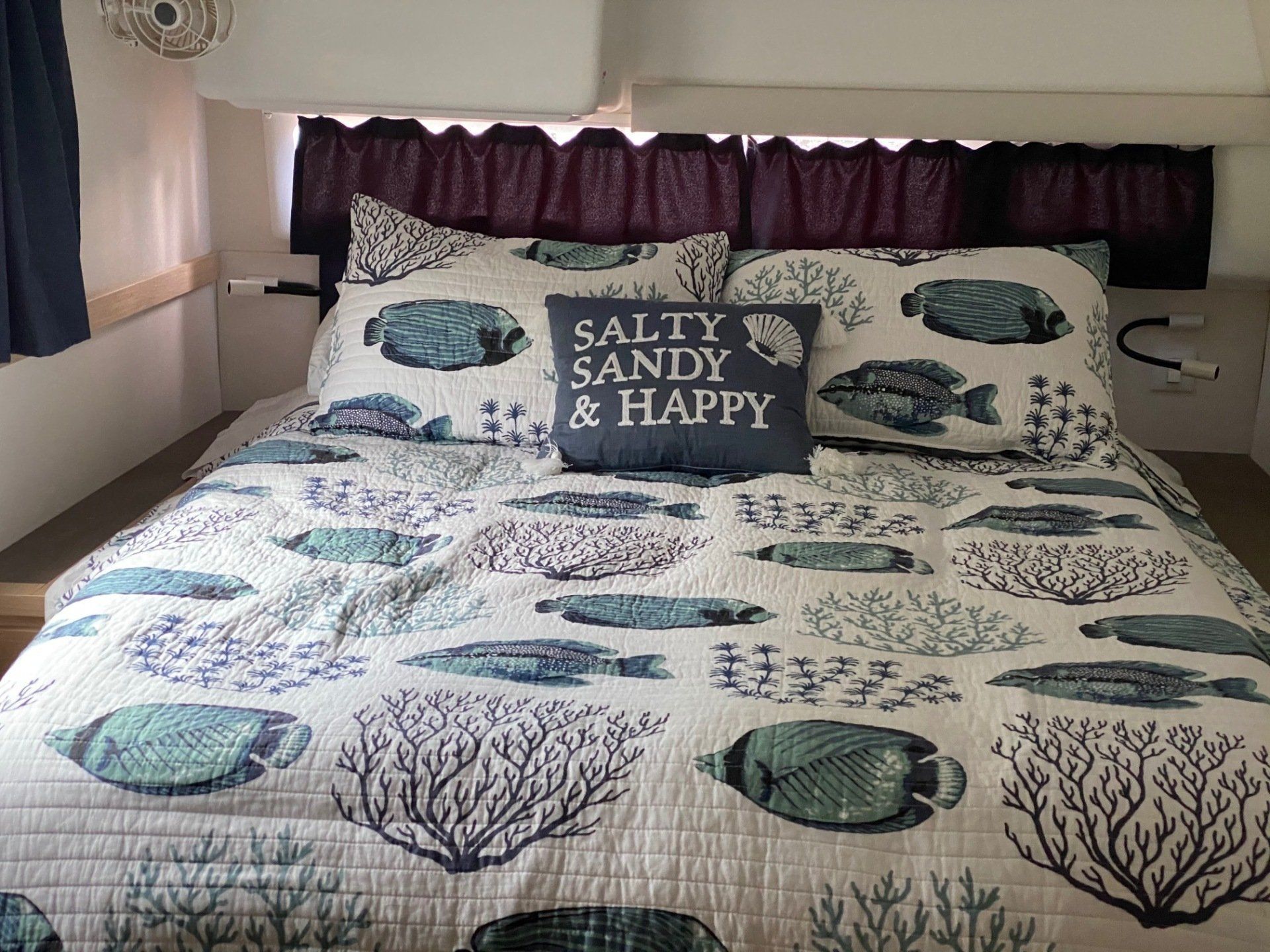 A bed with a pillow that says salty sandy and happy on it.
