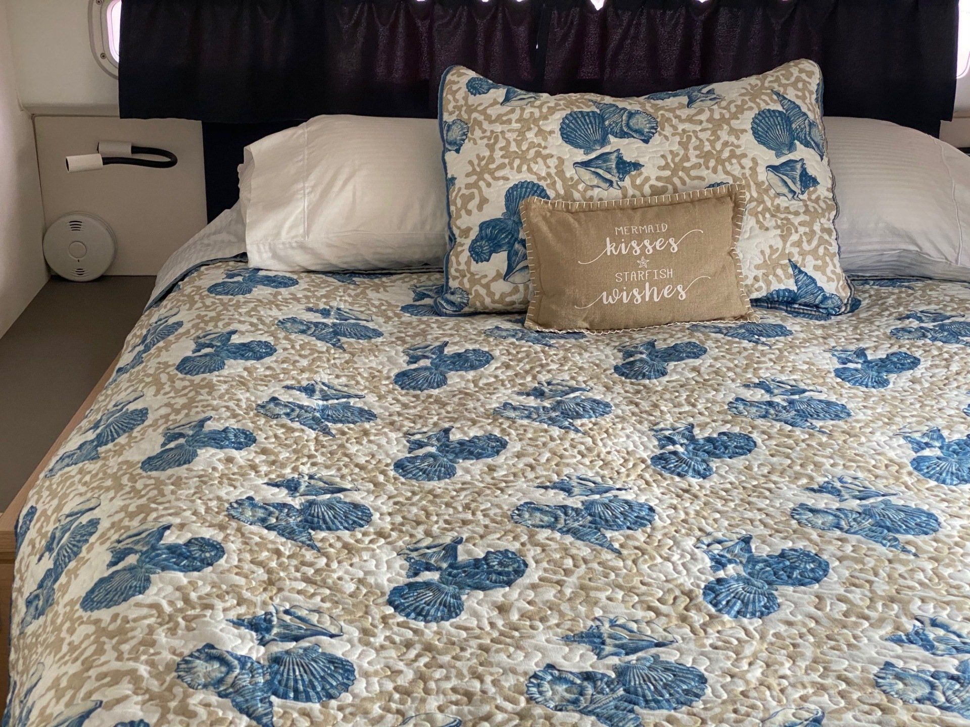 A bed with a blue and white blanket and pillows