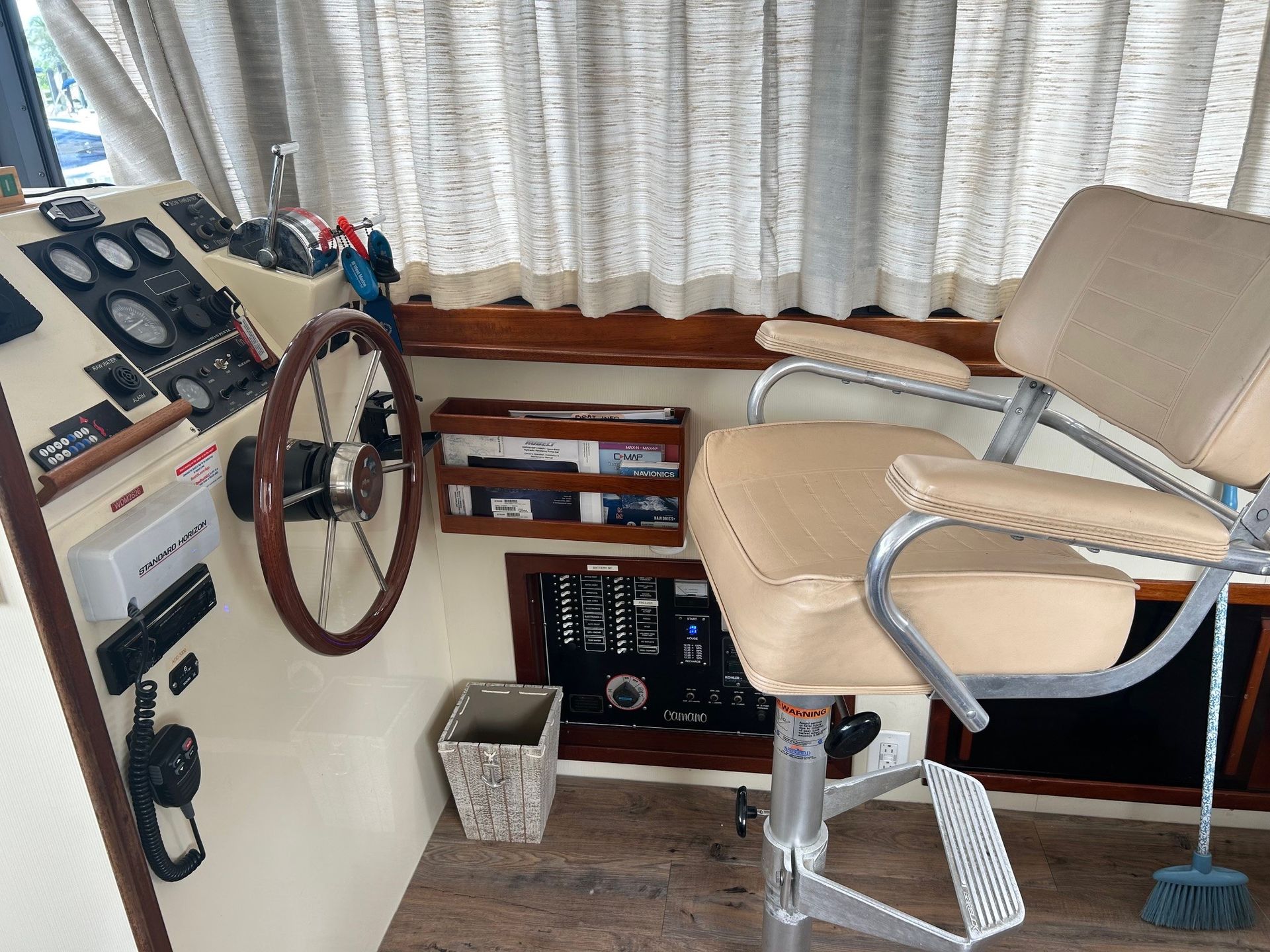 Interior boat cabin with steering wheel, helm chair, and gauges.