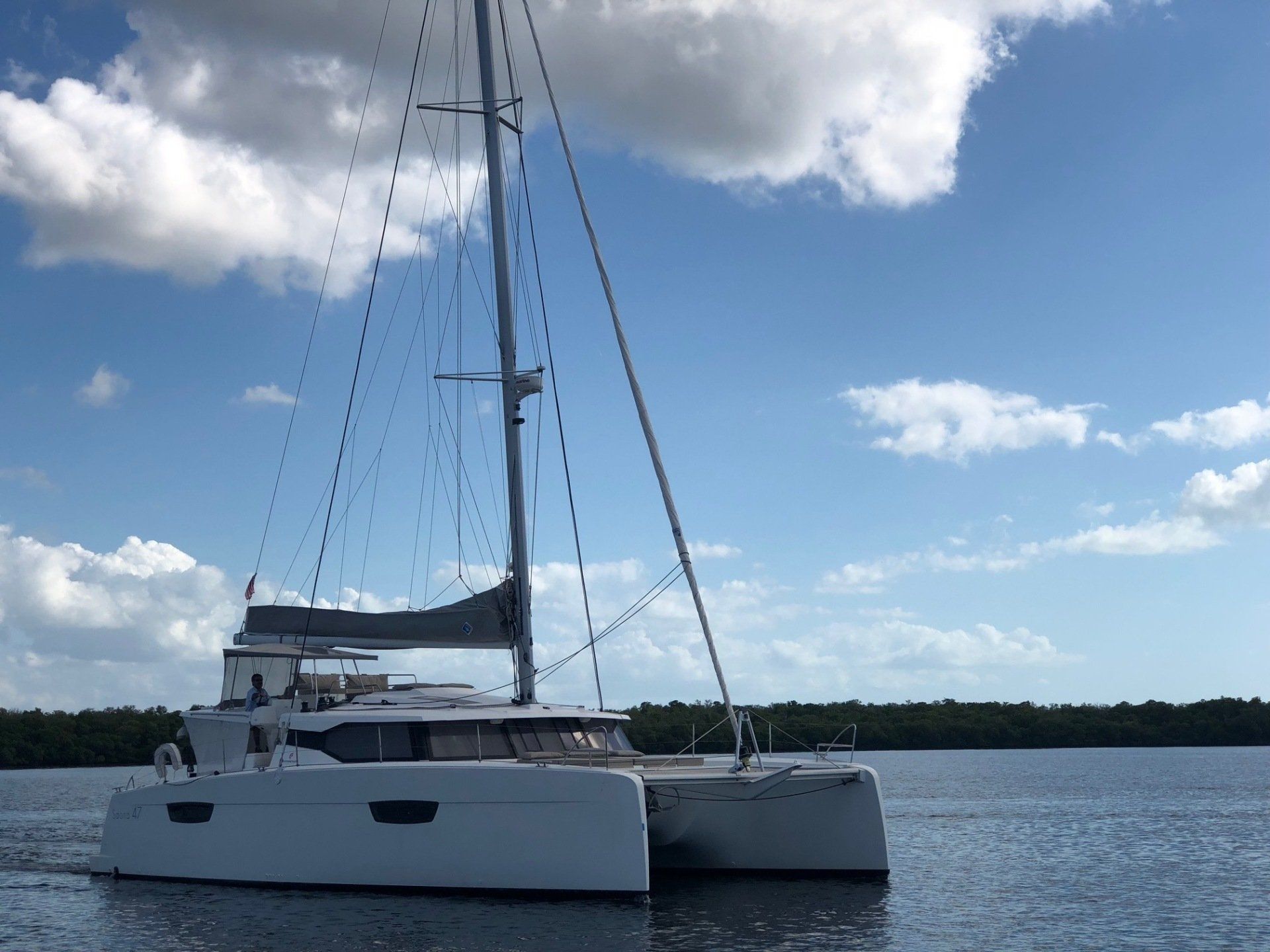 A white sailboat is floating on top of a body of water.