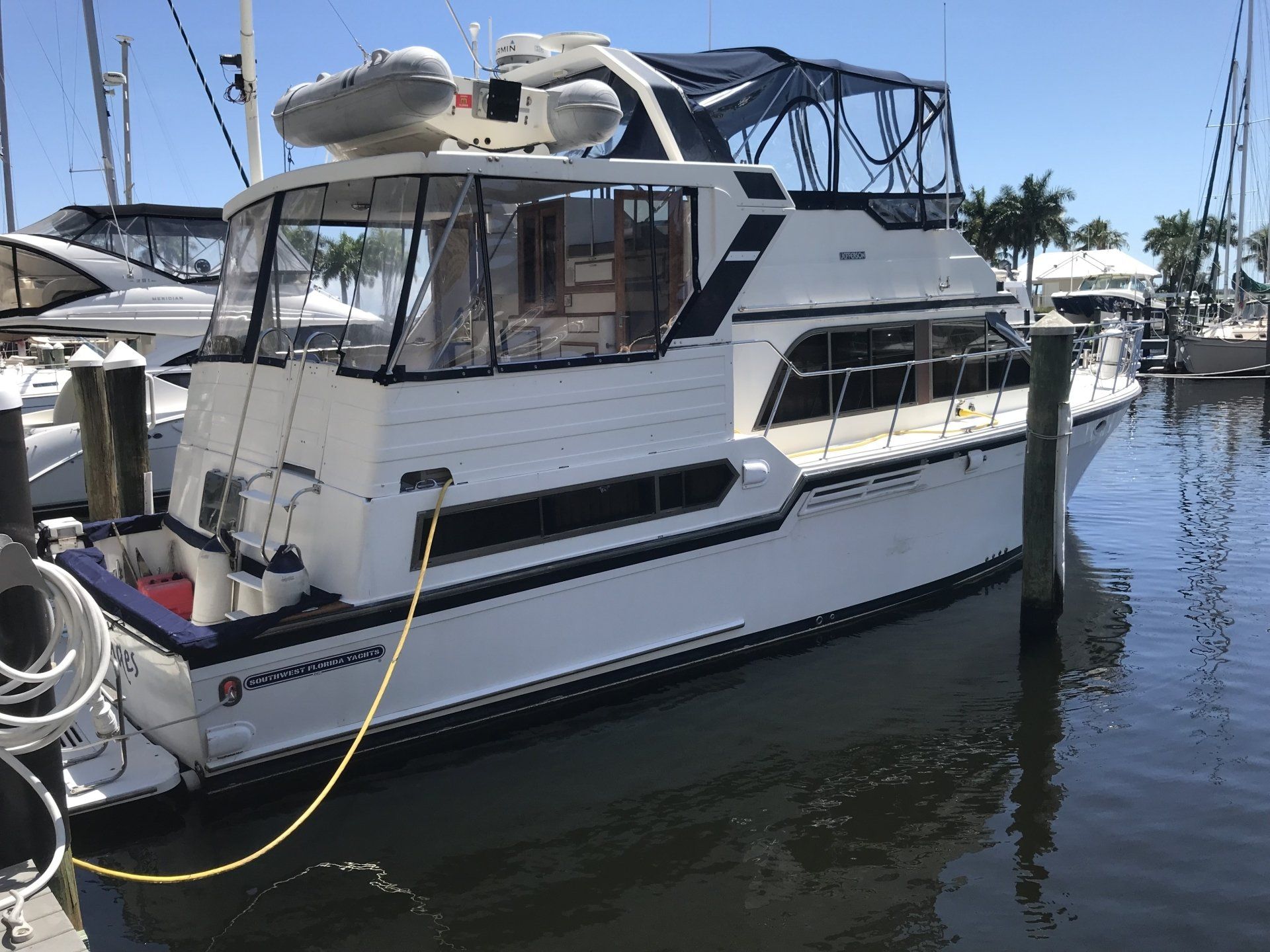 A boat is docked at a marina with a yellow hose attached to it.