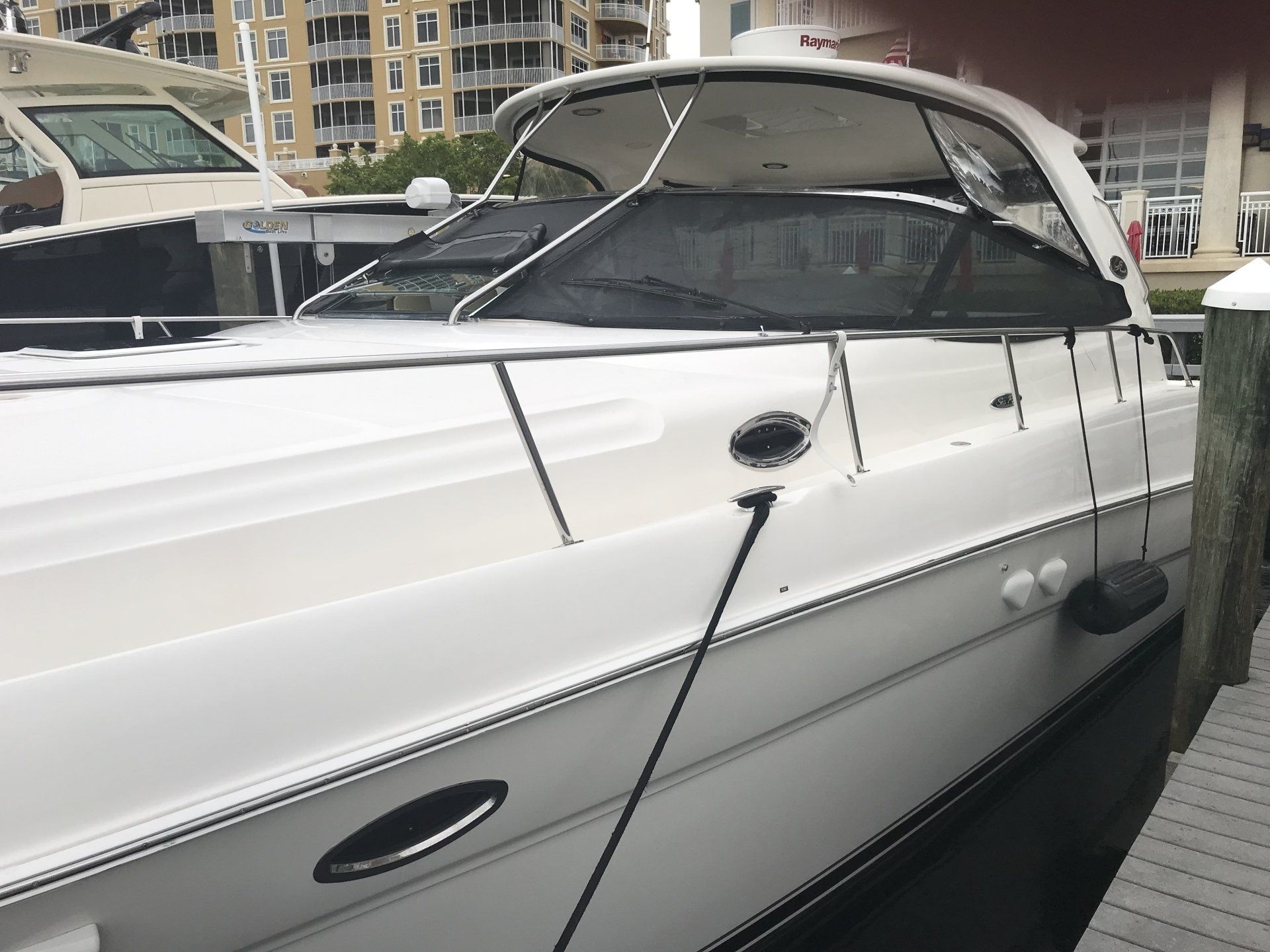 A white boat is docked at a dock next to a building.