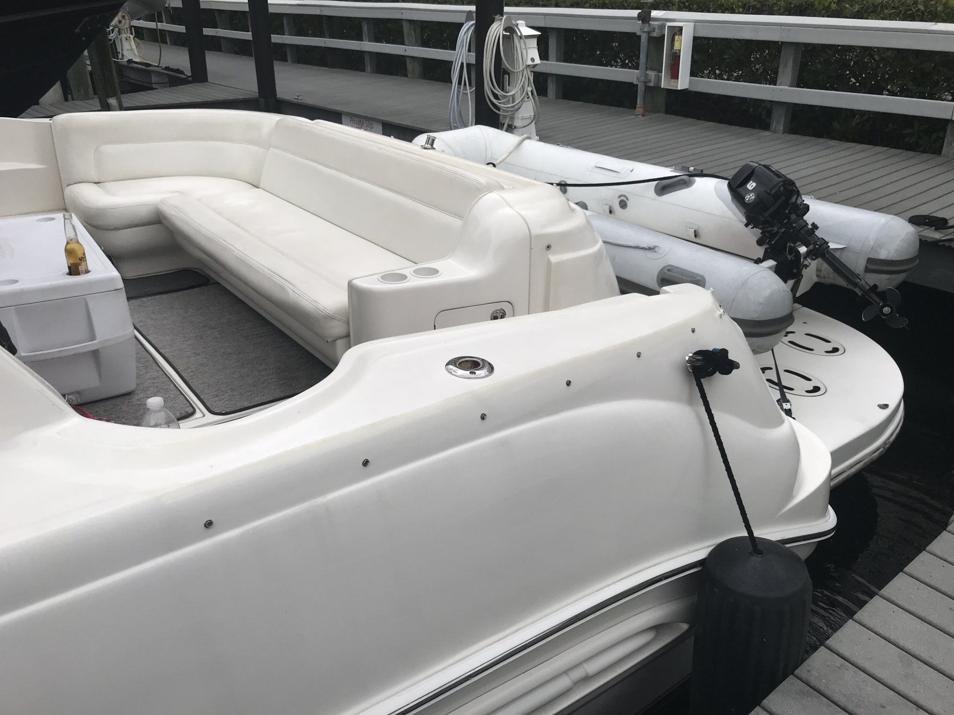 A white boat with a couch on the back is docked at a dock.