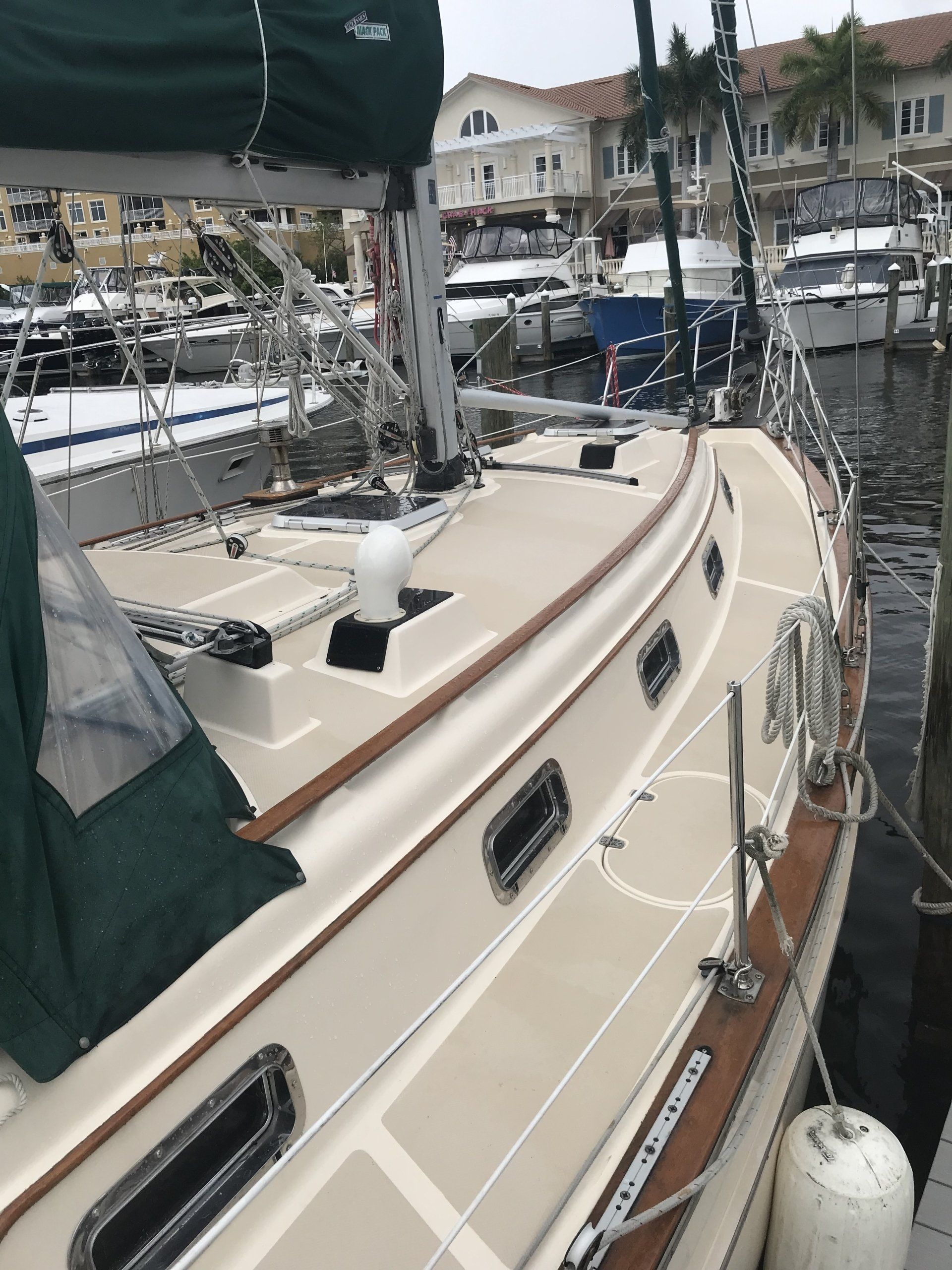 A sailboat with a green cover is docked in a marina