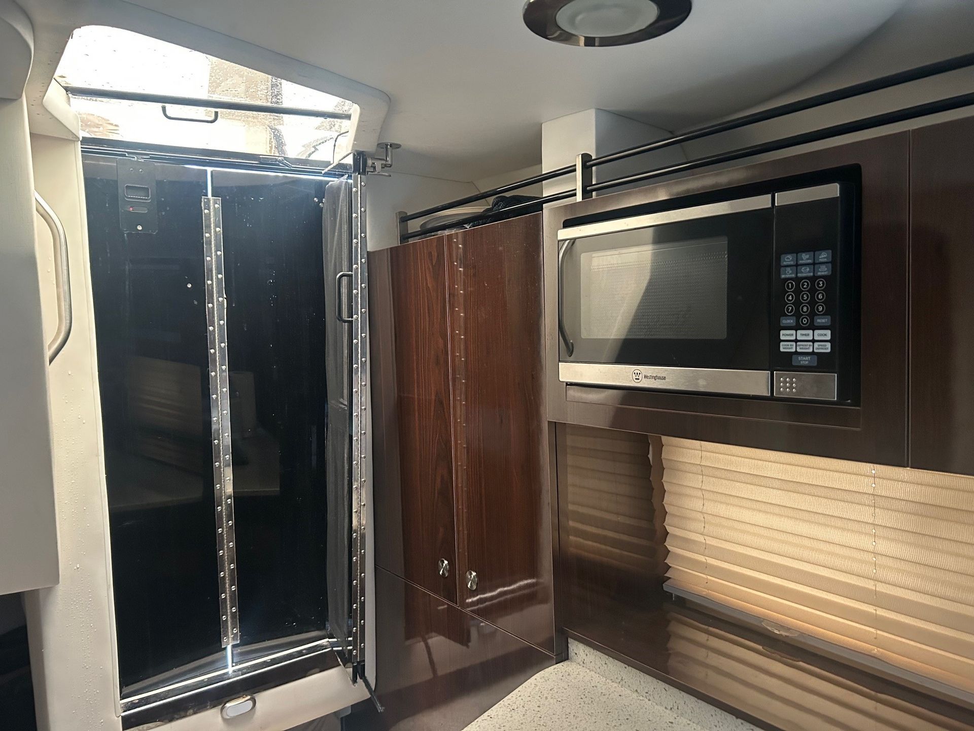 Interior of a boat cabin with a microwave, cabinet, and door to another area.
