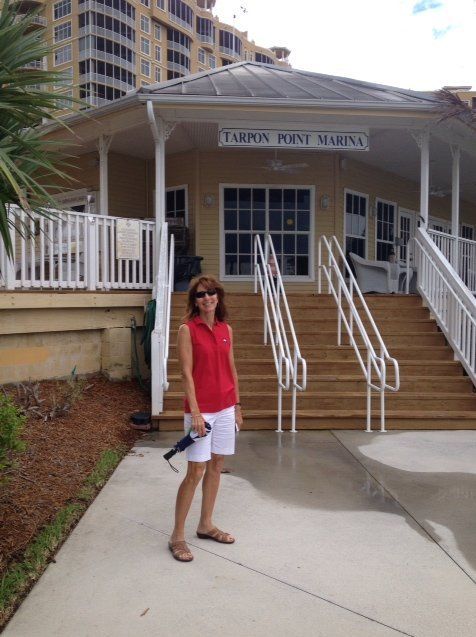 A woman is standing in front of a building that says tarpon point marina