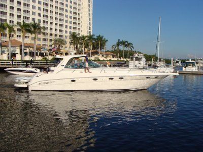 A white yacht is docked in a marina with palm trees in the background