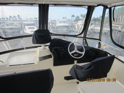 The inside of a boat with a steering wheel and chairs