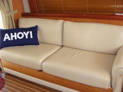 A white couch with a blue pillow that says ahoy !