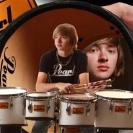 Teen drummer in black shirt, framed in a magnifying glass above a row of drums.