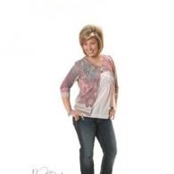 Woman posing in a pink cardigan, white top, and jeans against a white background