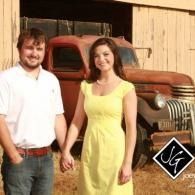 Couple holding hands in front of a rusty vintage truck outdoors