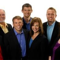 Group of five people posing in business attire against a white background