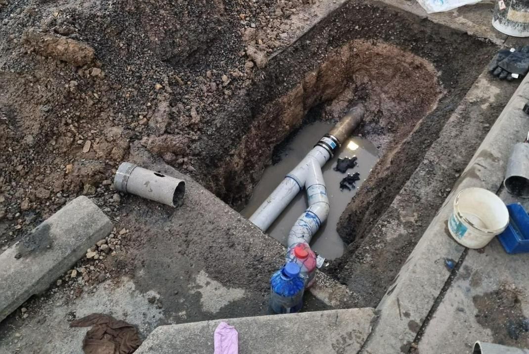 A Pipe Is Laying In The Dirt In A Hole — Bay City Plumbing in Pialba, QLD