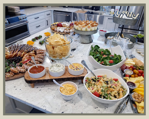 Buffet table with assorted salads, pastries, bread, and desserts in a bright kitchen